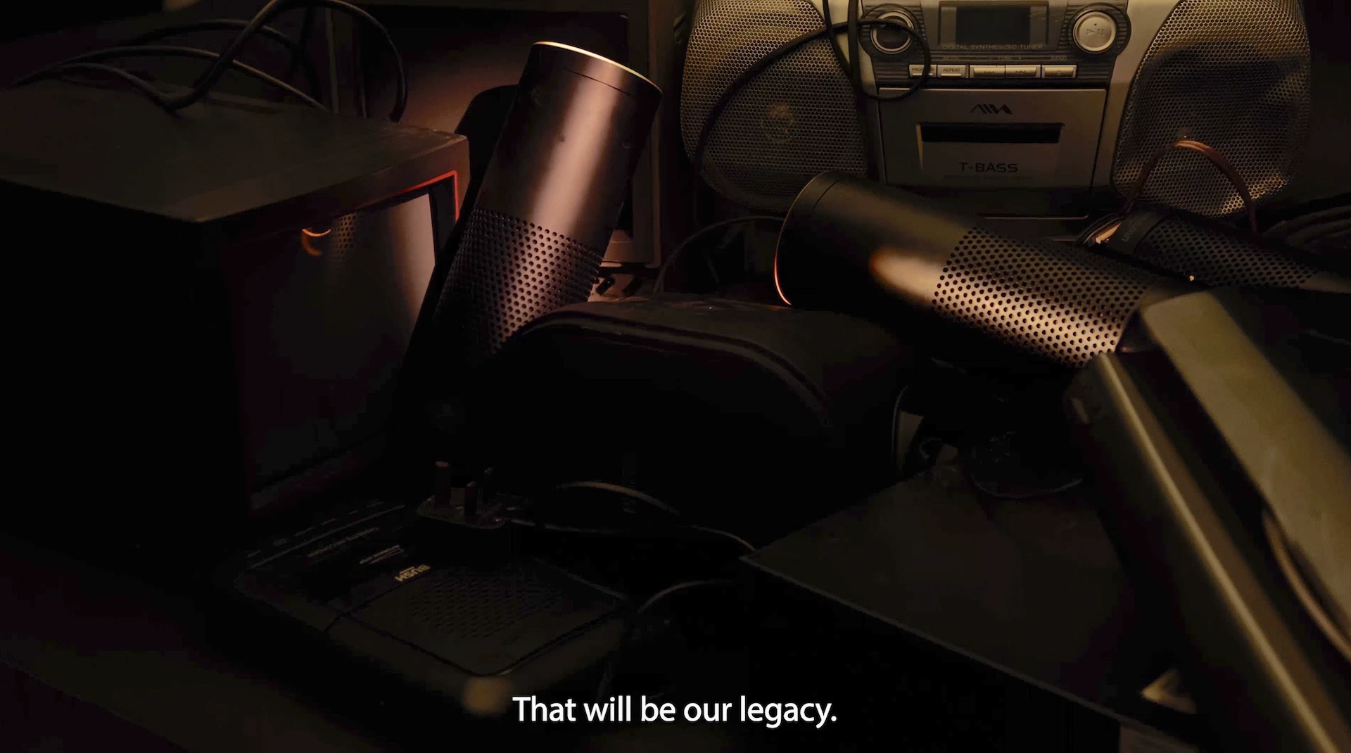 A pile of discarded Amazon Echoes with the phrase 'that will be our legacy' on subtitles.