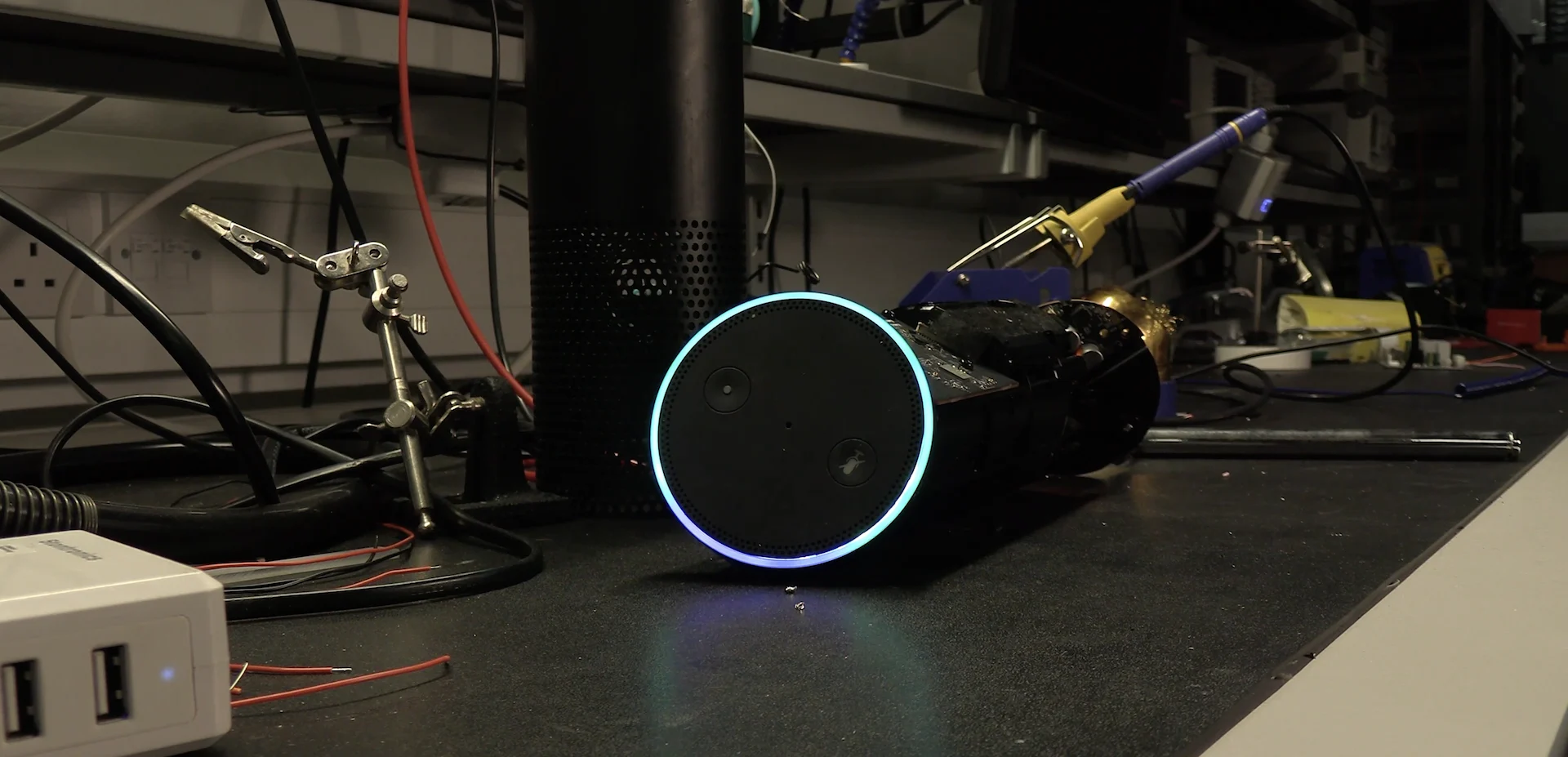 An image of an Amazon Echo being disassembled on a workbench.
