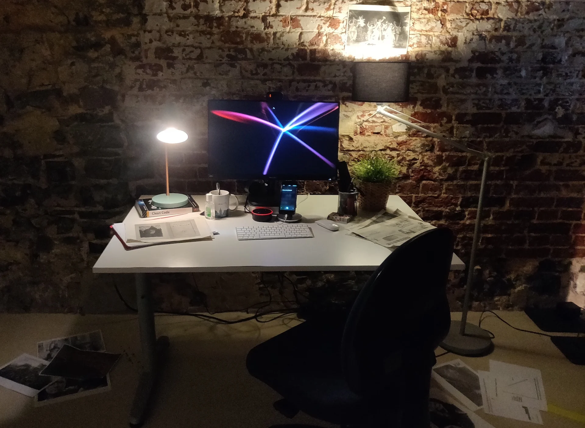 An image of a desk, with a screen, keyboard, and office ephemera, with a smartphone and Amazon Echo on it.