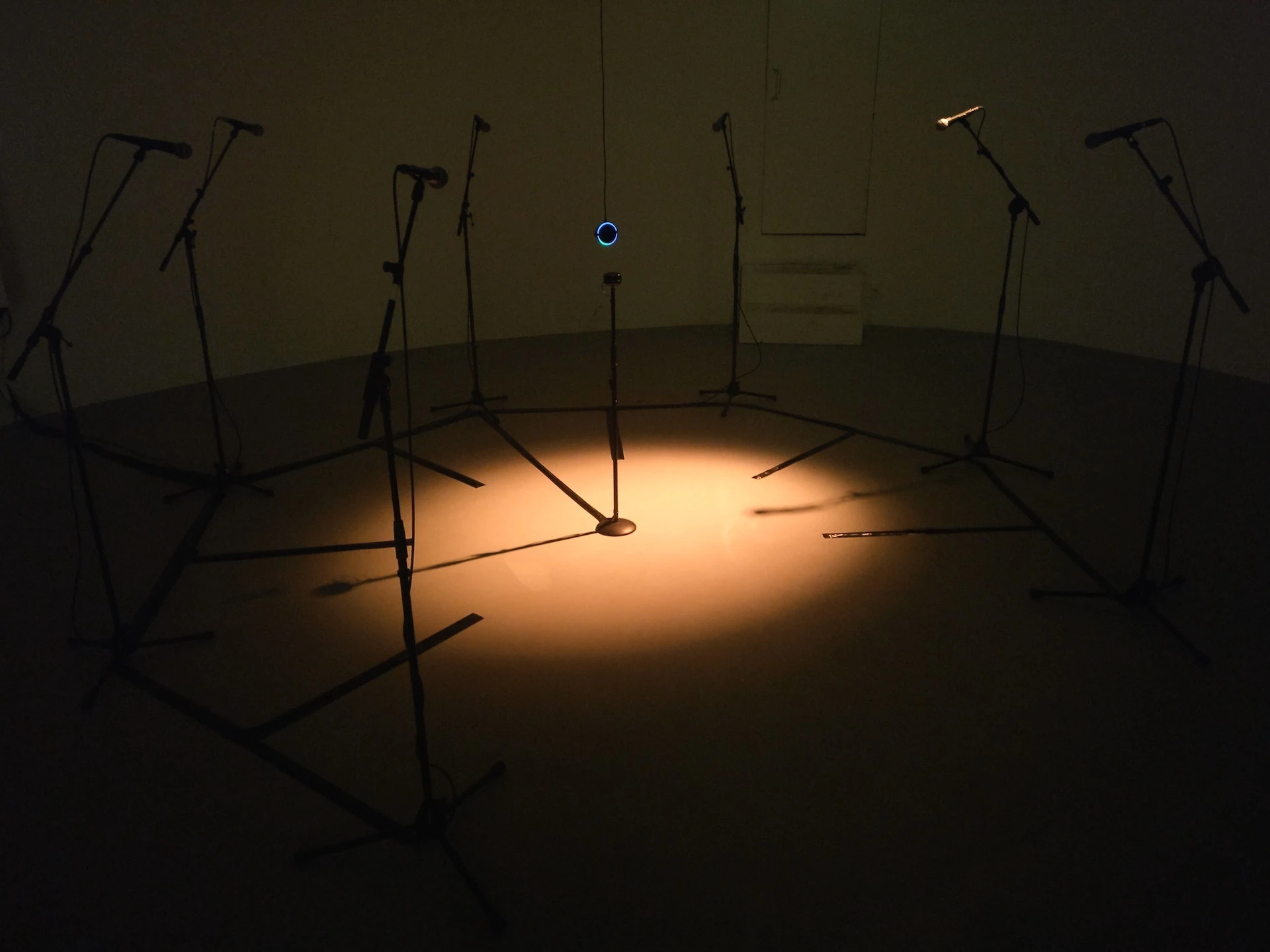 Installation view of the piece, an Amazon Echo suspend in the middle of the room, surrounded by a ring of microphones.
